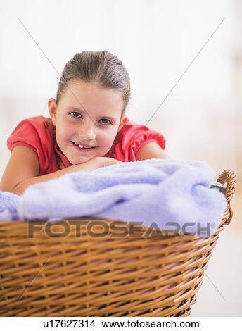 Picture - Young girl (8-9) leaning on laundry basket. Fotosearch