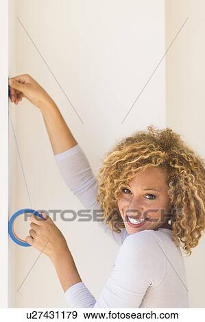 Young woman applying duct tape on wall View Large Photo Image Stock Photo - Young woman applying duct tape on wall. Fotosearch