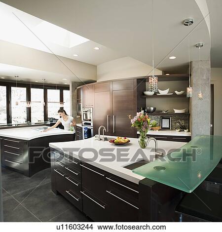 Young woman bustling around in modern domestic kitchen View Large Photo Image Picture - Young woman bustling around in modern domestic kitchen. Fotosearch