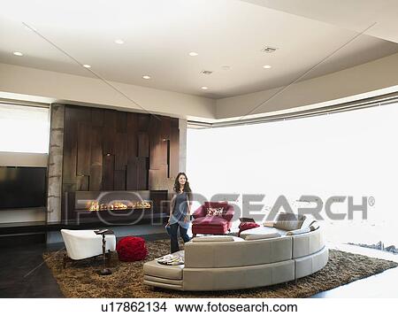 Young woman bustling in modern living room View Large Photo Image Picture - Young woman bustling in modern living room. Fotosearch