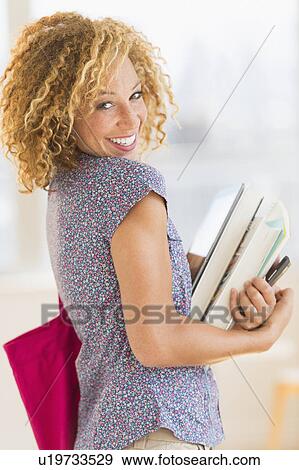 Young woman carrying books View Large Photo Image Stock Photo - Young woman carrying books . Fotosearch