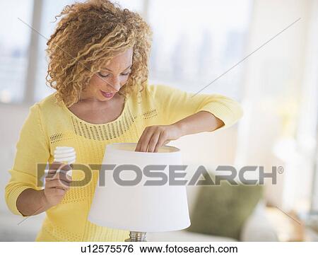 Young woman changing bulb in lamp View Large Photo Image Stock Photograph - Young woman changing bulb in lamp. Fotosearch