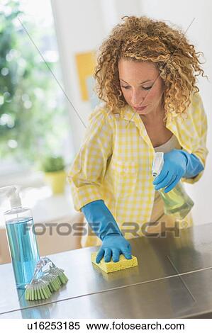 Stock Photography - Young woman cleaning in kitchen. Fotosearch