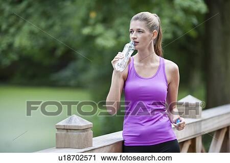 Young woman drinking water from bottle after running View Large Photo Image Stock Image - Young woman drinking water from bottle after running. Fotosearch
