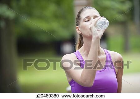 Young woman drinking water from bottle after running View Large Photo Image Stock Image - Young woman drinking water from bottle after running. Fotosearch