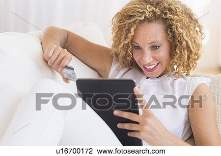Stock Image - Young woman e-shopping with digital tablet. Fotosearch