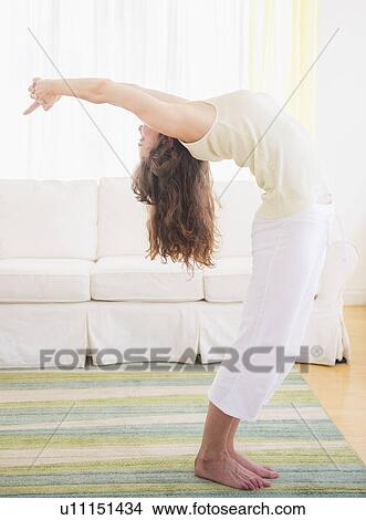 Picture - Young woman exercising at home. Fotosearch