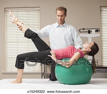 Stock Image - Young woman exercising with help from physical therapist. Fotosearch