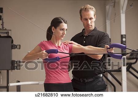 Stock Image - Young woman exercising with help from physical therapist. Fotosearch