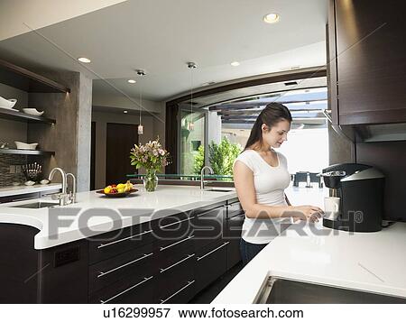 Stock Photo - Young woman making morning coffee. Fotosearch
