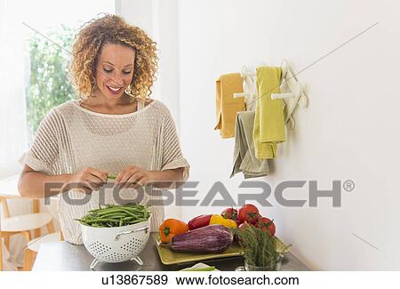 Young woman preparing food in kitchen View Large Photo Image Stock Photo - Young woman preparing food in kitchen. Fotosearch