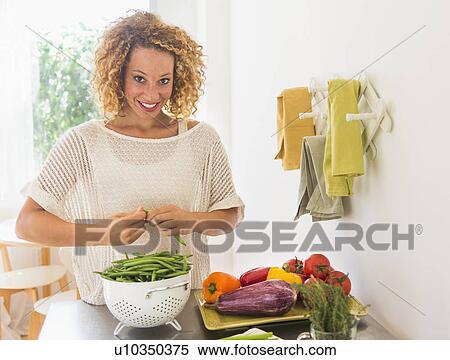 Stock Photography - Young woman preparing food in kitchen. Fotosearch