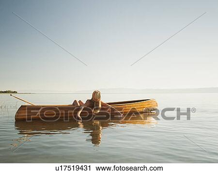 Stock Image - Young woman relaxing in canoe. Fotosearch