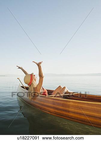 Young woman relaxing in canoe with arms raised View Large Photo Image Stock Image - Young woman relaxing in canoe with arms raised. Fotosearch
