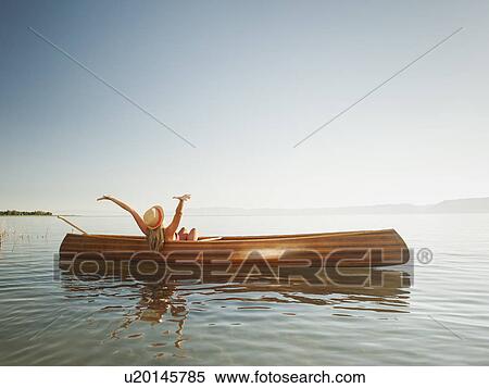 Young woman relaxing in canoe with arms raised View Large Photo Image Stock Photography - Young woman relaxing in canoe with arms raised. Fotosearch