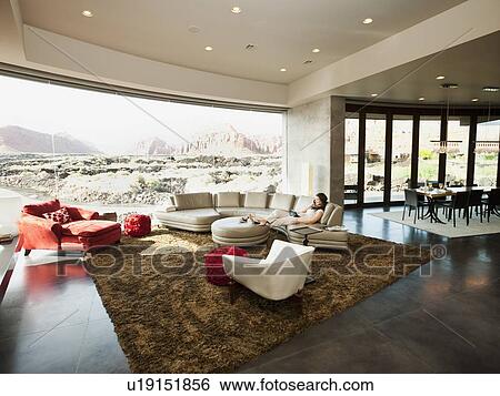 Young woman relaxing in her living room View Large Photo Image Stock Photograph - Young woman relaxing in her living room. Fotosearch