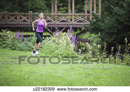 Young woman running in field View Large Photo Image Stock Photo - Young woman running in field. Fotosearch