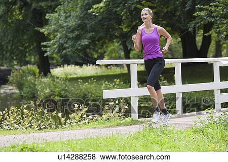 Young woman running over bridge in park View Large Photo Image Stock Photo - Young woman running over bridge in park. Fotosearch