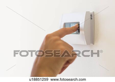 Stock Photo - Young woman setting air conditioning. Fotosearch