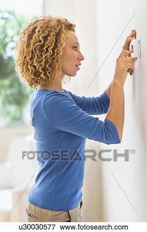 Stock Photo - Young woman setting air conditioning. Fotosearch