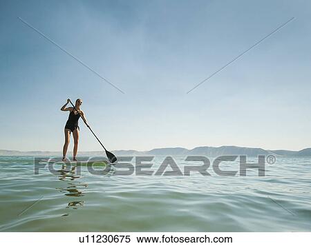 Young woman standing on paddleboard View Large Photo Image Stock Photography - Young woman standing on paddleboard. Fotosearch
