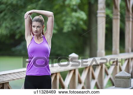 Young woman stretching arm on wooden bridge after running. View Large Photo Image Stock Photo - Young woman stretching arm on wooden bridge after running.. Fotosearch