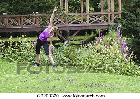 Young woman stretching her upper body in field View Large Photo Image Stock Image - Young woman stretching her upper body in field. Fotosearch
