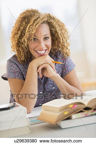 Stock Image - Young woman studying in library. Fotosearch