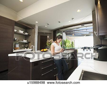 Young woman text-messaging in her kitchen View Large Photo Image Stock Photo - Young woman text-messaging in her kitchen. Fotosearch