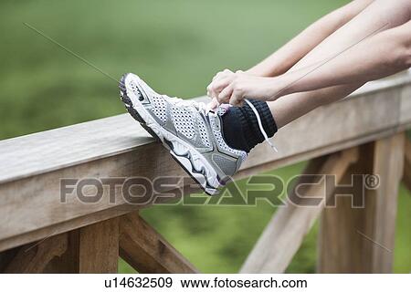 Stock Photo - Young woman tying her shoes. Fotosearch
