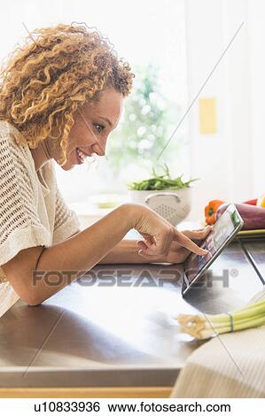 Young woman using digital tablet in kitchen View Large Photo Image Stock Photograph - Young woman using digital tablet in kitchen. Fotosearch