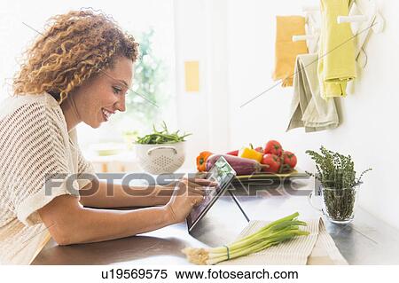 Young woman using digital tablet in kitchen View Large Photo Image Stock Photography - Young woman using digital tablet in kitchen. Fotosearch