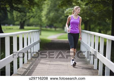 Young woman walking over bridge and looking over edge View Large Photo Image Stock Photo - Young woman walking over bridge and looking over edge. Fotosearch