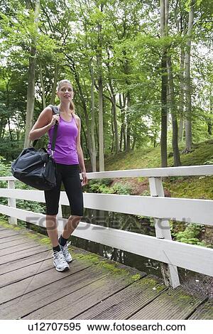 Young woman walking over bridge carrying sport bag View Large Photo Image Stock Photography - Young woman walking over bridge carrying sport bag. Fotosearch