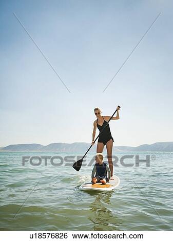 Stock Photograph - Young woman with daughter (4-5) on paddleboard. Fotosearch