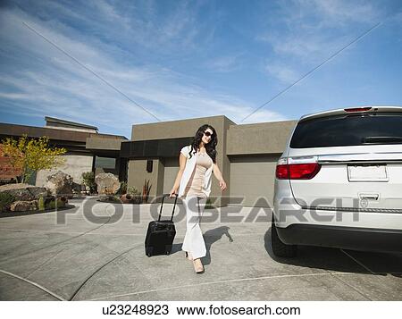 Young woman with suitcase walking towards car View Large Photo Image Stock Image - Young woman with suitcase walking towards car. Fotosearch