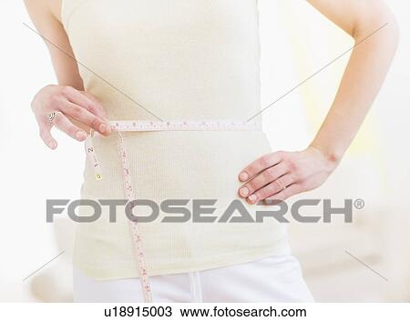Young woman with tape measure wrapped around waist, midsection View Large Photo Image Stock Image - Young woman with tape measure wrapped around waist, midsection. Fotosearch