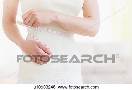 Young woman with tape measure wrapped around waist, midsection View Large Photo Image Stock Photograph - Young woman with tape measure wrapped around waist, midsection. Fotosearch