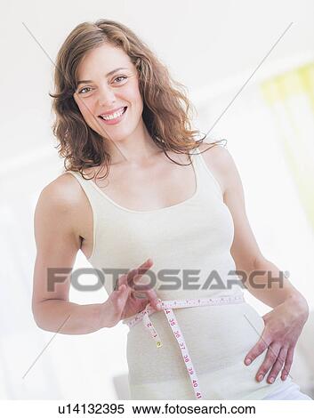 Young woman with tape measure wrapped around waist View Large Photo Image Stock Photography - Young woman with tape measure wrapped around waist. Fotosearch