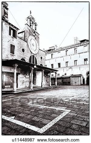 Stock Photo - A small piazza near the Rialto Bridge, with church facade and sundial, decorated paving, monochrome image, Venice, Italy. Fotosearch