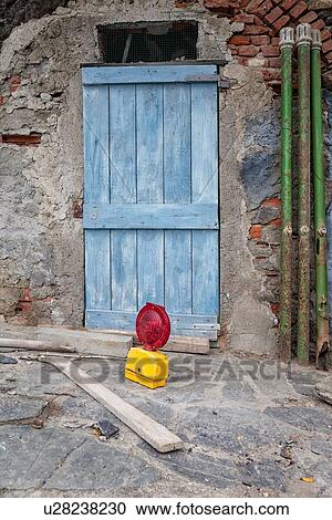 Blue wooden plank door with crumbling stone wall, green pipes, and workman's red and yellow sign with planks in front on stone pathway, Monterosso al Mare, Cinque Terre. Liguria, Italy View Large Photo Image Stock Image - Blue wooden plank door with crumbling stone wall, green pipes, and workman's red and yellow sign with planks in front on stone pathway, Monterosso al Mare, Cinque Terre. Liguria, Italy. Fotosearch