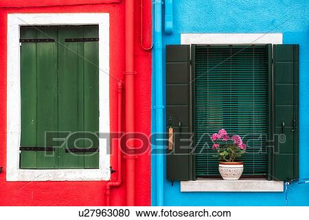 Burano: house detail close up with brightly painted red wall, blue wall, door with green wooden shutters and second window with green blinds and flower pot on sill with pink geraniums, Venice, Italy View Large Photo Image Stock Image - Burano: house detail close up with brightly painted red wall, blue wall, door with green wooden shutters and second window with green blinds and flower pot on sill with pink geraniums, Venice, Italy. Fotosearch