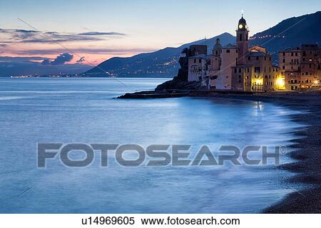 Stock Photography - Camogli: beach and sea with motion blur, church tower and sea front buildings, blue twilight sky with dramatic clouds, night lights, Liguria, Italy. Fotosearch