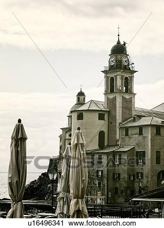 Camogli: church tower and surrounding buildings with closed beach umbrellas in foreground, sea beyond, monochrome image, Liguria, Italy View Large Photo Image Stock Image - Camogli: church tower and surrounding buildings with closed beach umbrellas in foreground, sea beyond, monochrome image, Liguria, Italy. Fotosearch