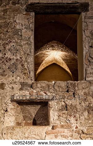 Stock Photo - Church of San Francesco with detail of cantina (underground) storage and wine making area: stone wall with red and blue stencil, vaulted stone ceiling seen through window area, Montefalco, Umbria, Italy. Fotosearch