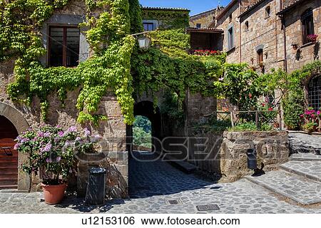 Cività di Bagnoregio: centre of village, with ivy covered stone houses, cobblestone piazza, arched walkway leading to bridge and treed valley beyond, Umbria, Italy View Large Photo Image Stock Photograph - Cività di Bagnoregio: centre of village, with ivy covered stone houses, cobblestone piazza, arched walkway leading to bridge and treed valley beyond, Umbria, Italy. Fotosearch