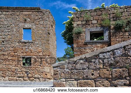 Stock Image - CivitÃ di Bagnoregio: detail of stone buildings in ruins against sunny blue sky background, Umbria, Italy. Fotosearch