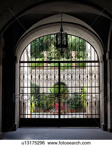 Close up of wrought iron gate with courtyard of flowers and plants in terrracotta vases beyond, and more planters on raised wall with trees beyond, Orvieto, Umbria, Italy View Large Photo Image Stock Photograph - Close up of wrought iron gate with courtyard of flowers and plants in terrracotta vases beyond, and more planters on raised wall with trees beyond, Orvieto, Umbria, Italy. Fotosearch