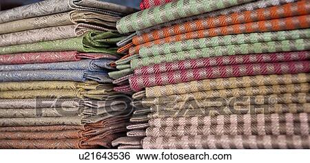 Stock Photograph - Close up view of display of linen and cotton tablecloths woven on Jacquard loom, 2 piles on shelf, Umbria, Italy. Fotosearch