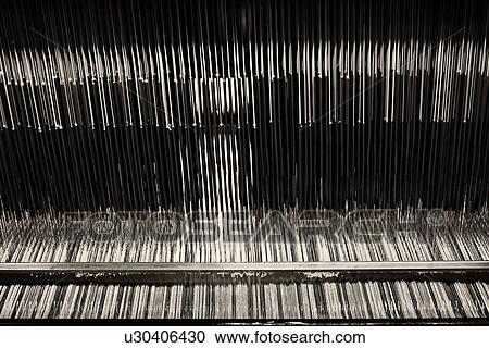 Stock Image - Close up view of Jacquard loom with pattern formed by linen and cotton threads attached, high key monochrome image, Umbria, Italy. Fotosearch